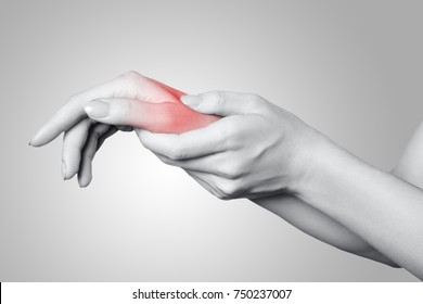 Closeup View Of A Young Woman With Pain On Hand On Gray Background. Black And White Photo With Red Dot.