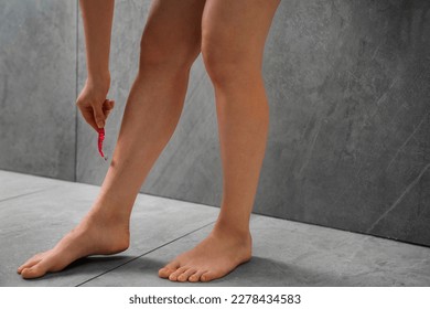 close-up view of young woman shaving leg in bathroom. Close up woman shaving leg while relaxing in shower.