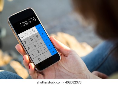 close-up view of young woman using calculator app on her mobile phone. All screen graphics are made up.