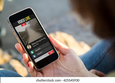 Close-up View Of Young Woman Watching A Live Video On Her Mobile Phone. All Screen Graphics Are Made Up.