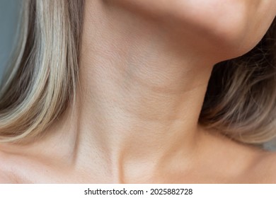 A close-up view of a young woman's neck and collarbone . Lines on the neck. Wrinkles, age-related changes, rings of Venus, goosebumps. Skin care. Close-up
