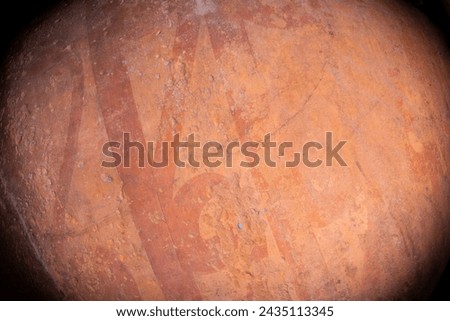 A closeup vignetted shot of the side of the red brown clay amphora with faded darker linear ornament.