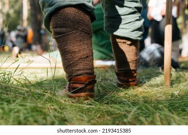 Close-up Of A Viking Leg In Protective Braid. Warrior Standing On Grass Outdoors, Low Angle View.