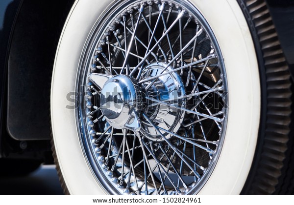 Closeup of vintage car wire wheel tyre. Retro car\
tire with silver wired\
disc