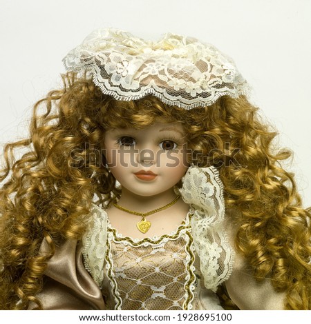 a closeup of a vintage Doll with beautiful golden tresses on a white background