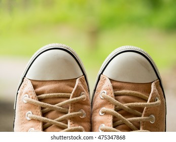 Closeup Of Vintage Soft Brown Woman Sneaker Shoes On Blur Green Nature In Background. Travel Adventure And Journey Concept.