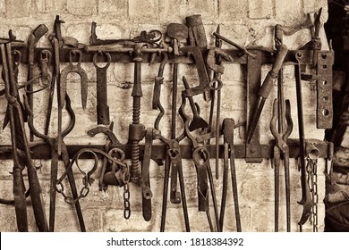 Close-up of vintage work tools hanging on rack at blacksmith shop