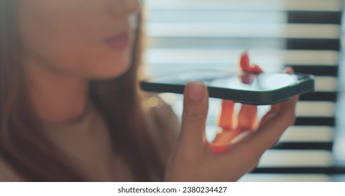 Close-up voice control of a smart home on a mobile phone. Talking in the speaker of a young woman. Send voice message, use phone app leave voicemail response. - Powered by Shutterstock