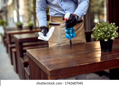 Close-up Of Waiter Cleaning Tables At Outdoor Cafe After Reopening. 