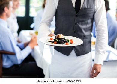 Close-up Of Waiter Holding Plate Of Meal In Restaurant