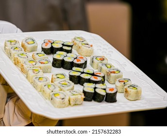 A Closeup Of A Waiter Holding A Plate Of Sushi Assortment In A Restaurant