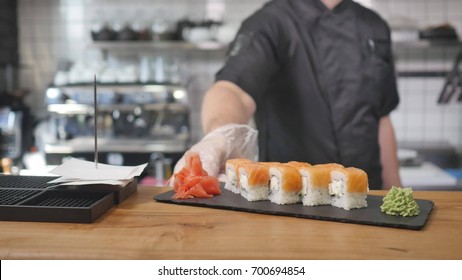 Close-up - The Waiter Put The Sushi On Board On The Table In Restaurant.