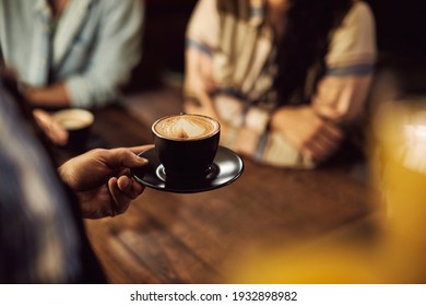 Close-up of waiter serving coffee to customers while working in a cafe.  - Powered by Shutterstock