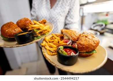 Close-up of a waiter serving gourmet burgers and fries on a tray. focus is on the appetizing food, perfect for culinary or hospitality themes. photos showcasing delicious meals and restaurant service. - Powered by Shutterstock