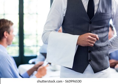 Close-up Of Waiter Standing With Napkin In Restaurant