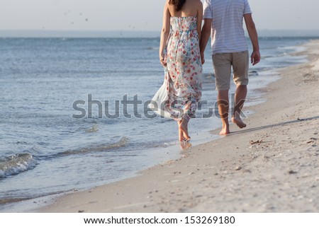 Closeup of walking couples feet along the paradises coast of sea or ocean. white clear sand. small blue clear waves