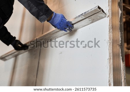 Close-up of the wall alignment rule tool. A man is smoothing a layer of plaster on a wall. With space to copy. High quality photo