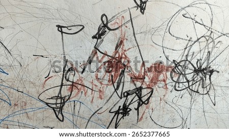 Close-up of a wall with chaotic scribbles in black, red, and blue ink. Abstract child-like doodles on a scratched white surface, showing raw artistic expression