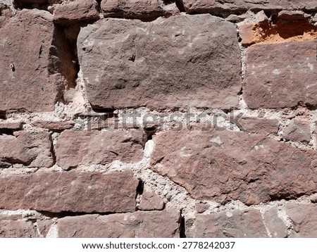 Close-up of a wall made of irregular red sandstone blocks in the sunlight, Freiburg, Germany