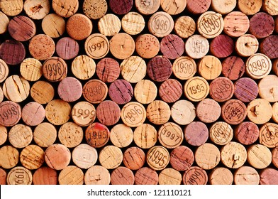 Closeup of a wall of used wine corks. A random selection of used wine corks, some with vintage years. Horizontal format that fills the frame.
