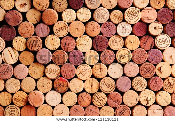 Closeup of a wall of used wine corks. A random\
selection of used wine corks, some with vintage years. Horizontal\
format that fills the\
frame.