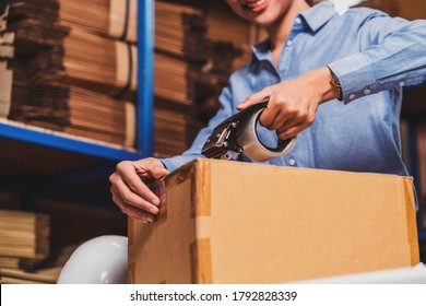 Closeup of Warehouse worker woman packing cardboard box with sticky tape with Indian worker man in local warehouse or factory, industry and export business concept, partner and colleague work together