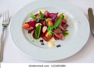 Close-up Of A Warm Salad With Roast Beef. Cherry Pickers, Basil, Sauce, Spices. Very Tasty, Lunch, Dinner. Beautiful Feed. View From Above