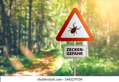 Close-up Of Warning Sign With Text ZECKEN GEFAHR, German For Beware Of Ticks, Against Defocused Forest Background