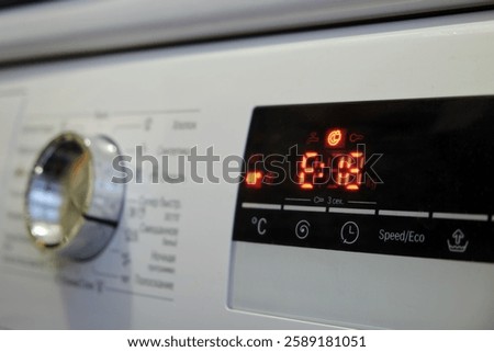 Close-up of a washing machine control panel with a digital display and a error code E18. The red LED screen shows the washing time and temperature settings. Home appliance concept.