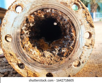 Closeup of waste in old water pipes Clogged debris and corroded rust in old plumbing pipes on the cement courtyard background. Maintenance of water supply system. Selective focus