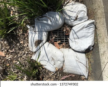 Closeup Of A Water Drain With A Metal Grate Surrounded By White Sandbags.