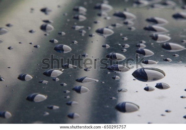 Closeup of Water Droplets from Rain\
on Blue Car Hood Reflecting a Condo and the South Florida\
Sky