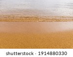 Close-up of a water edge and yellow sand summer beach background with copy space.