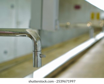 A close-up of a water faucet with a beautifully blurred background, emphasizing the clean, sleek lines of the tap. - Powered by Shutterstock