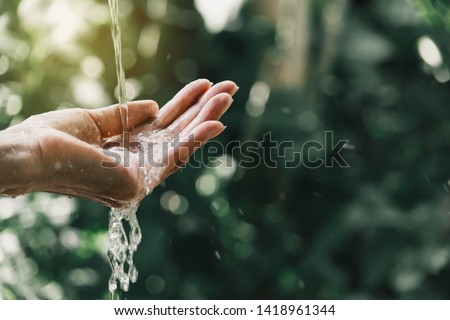 closeup water flow to hand of women for nature concept on the garden background.
