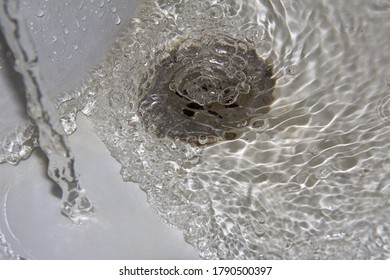 Close-up Of Water Flowing From Faucet In Bathroom Sink. Bubbles In Water