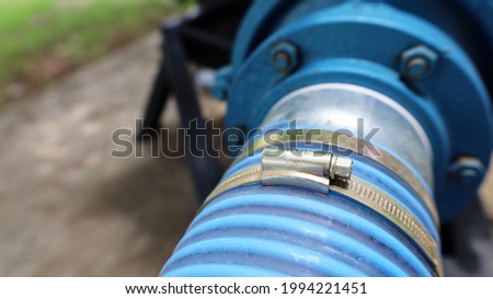 Close-up of the water pump hose clamp. The soft plastic hose is connected to the blue pumping pump with copy space. Selective focus