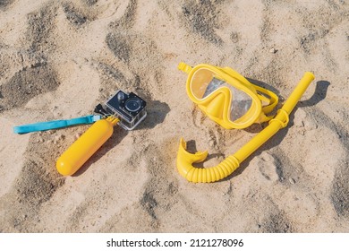 Close-up waterproof action cameras with a yellow float in the sand on the beach. Against the background of an underwater mask with a diving tube. Summer beach holiday concept