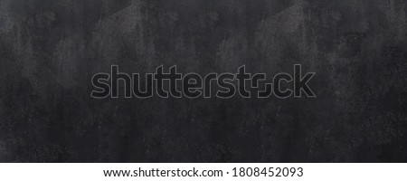 Close-up of a weathered and aged dark gray, almost black, concrete wall, texture background.