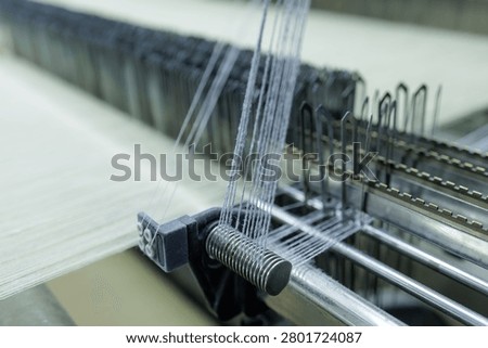 Close-up of a weaving machine in action at a wool production factory, showcasing the spinning process and intricate machinery involved in textile manufacturing.