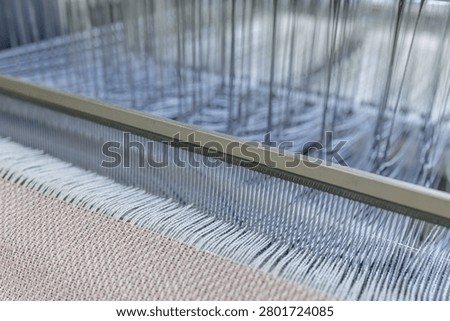Close-up of a weaving machine in a wool production factory, showcasing the intricate process of spinning and weaving threads into fabric.