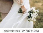 Close-up wedding couple bride and groom walk hand in hand through a pine forest, sunlight filtering through the trees, high lighting their joyful expressions.