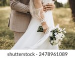 Close-up wedding couple bride and groom walk hand in hand through a pine forest, sunlight filtering through the trees, high lighting their joyful expressions.