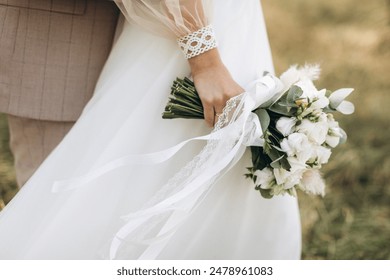 Close-up wedding couple bride and groom walk hand in hand through a pine forest, sunlight filtering through the trees, high lighting their joyful expressions.