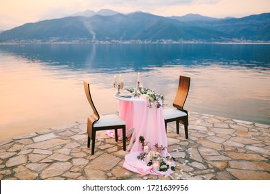 Close-up of a wedding dinner table at reception. Romantic sunset dinner on beach. A table by the sea, at sunset. Dinner for two. Romantic date