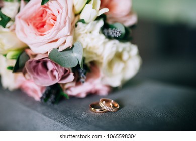 close-up of wedding rings on background wedding bouquet of roses and pions of berries and greens with lavender - Powered by Shutterstock