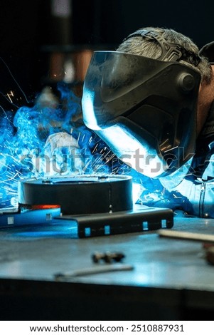 Close-up of a welder focused on his work, bright blue light and sparks emanating from the welding torch.
