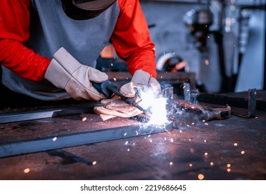 Close-up, welders wear gloves while using welding machines to weld steel workpieces. - Powered by Shutterstock
