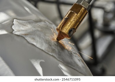 A close-up of a welding process, showing a brass welding torch creating sparks on a metallic surface, with visible grinding marks and reflections. Industrial and mechanical context. - Powered by Shutterstock