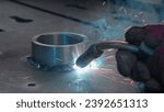 Close-up welding with sparks and metal ring. Creative. Welder welds metal ring with sparks. Sparks from welding with metal ring at factory or in forge